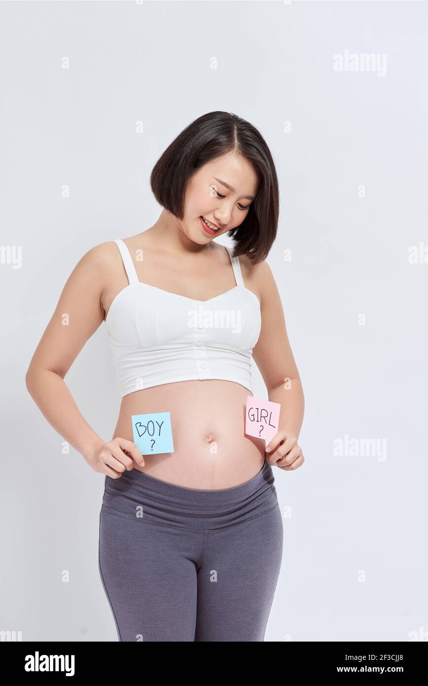 Pregnant woman with a sticky note and writing love boy or girl on sticky note and add on her belly,P Stock Photo