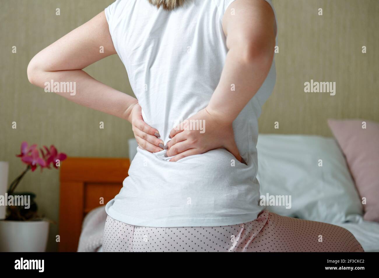 Back pain woman getting after wake up. Sick person with lower back pain. Unrecognizable woman in