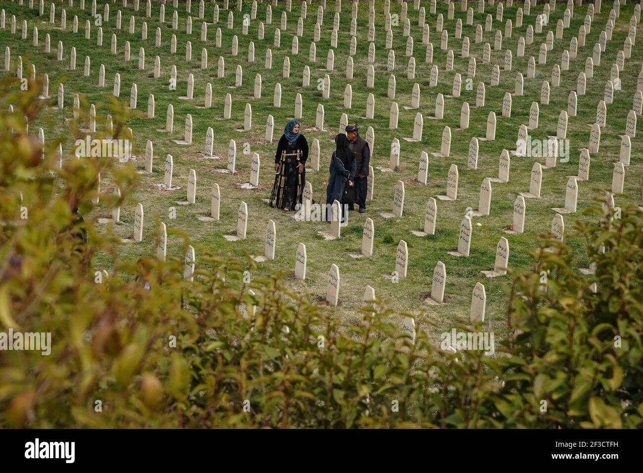 Halabja, Iraq. 16th Mar, 2021. A family visits the grave of their lost ones at Halabja Cemetery on the 33rd anniversary of Halabja chemical attack, which killed nearly 5000 people and injured about 10000, most of them were civilians. Credit: Ismael Adnan/dpa/Alamy Live News Stock Photo