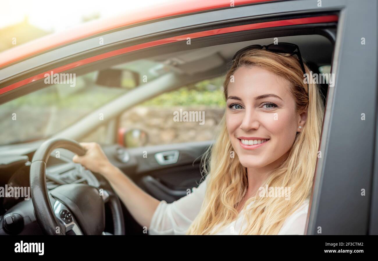 Happy beautiful woman is driving a red car Stock Photo - Alamy