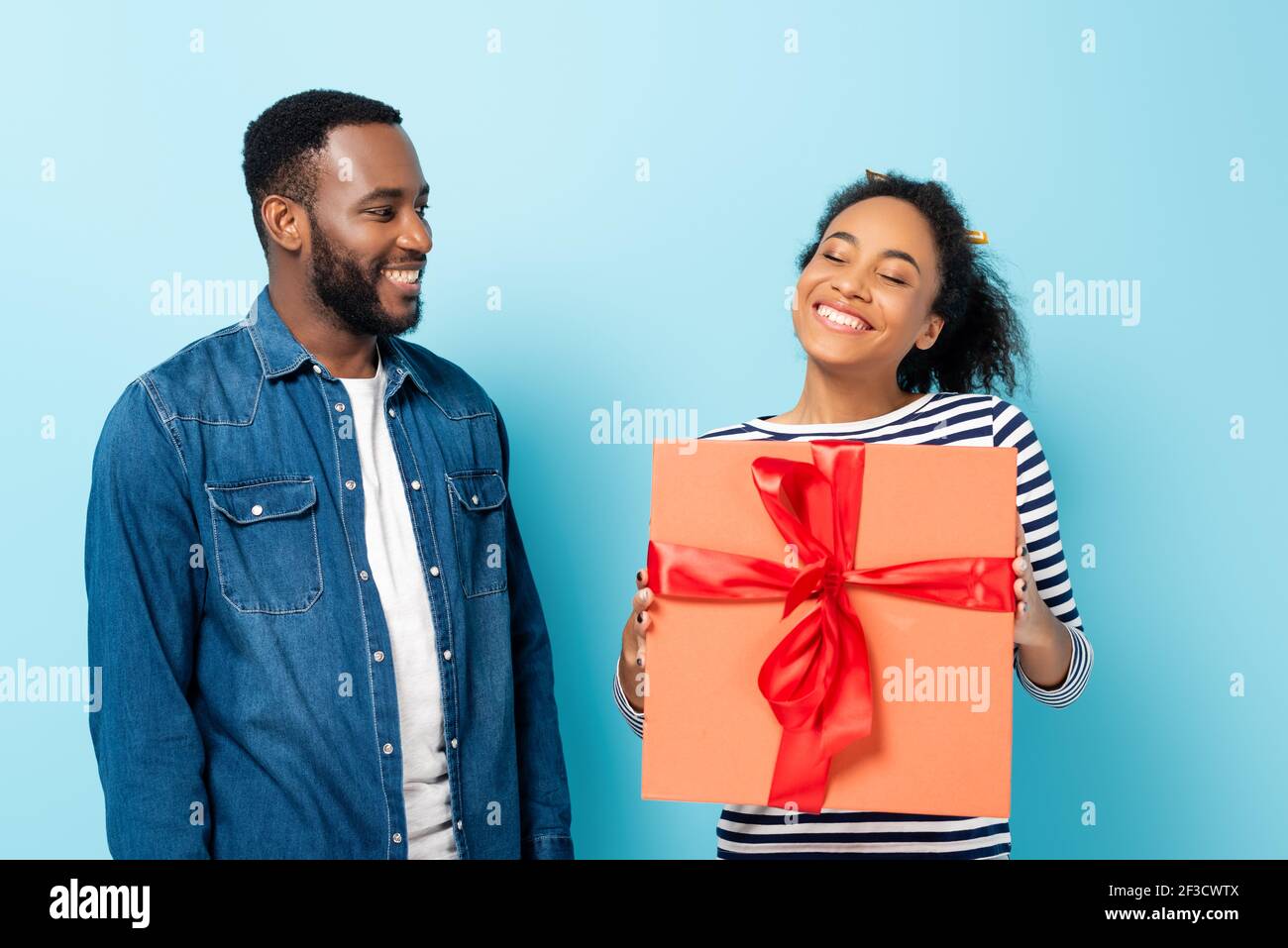 happy african american woman holding big gift box near smiling husband ...