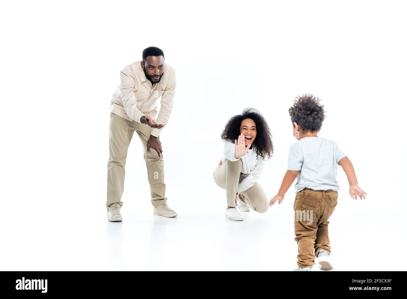 excited african american woman giving high five to toddler son walking on white Stock Photo