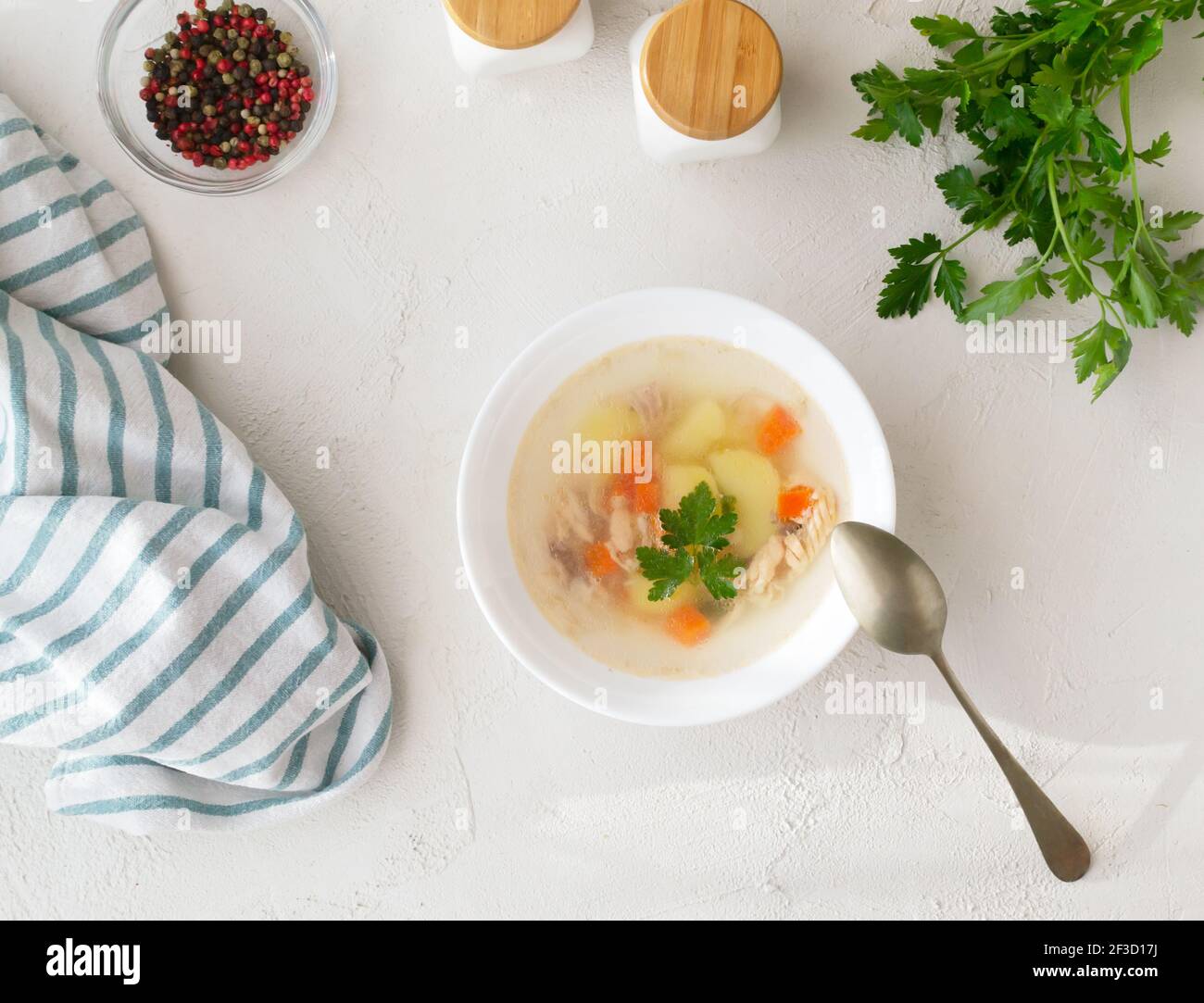 Clear fish soup with pieces of vegetables and salmon in a white bowl on a white plate. Healthy food concept. Top view. Horizontal orientation. Stock Photo