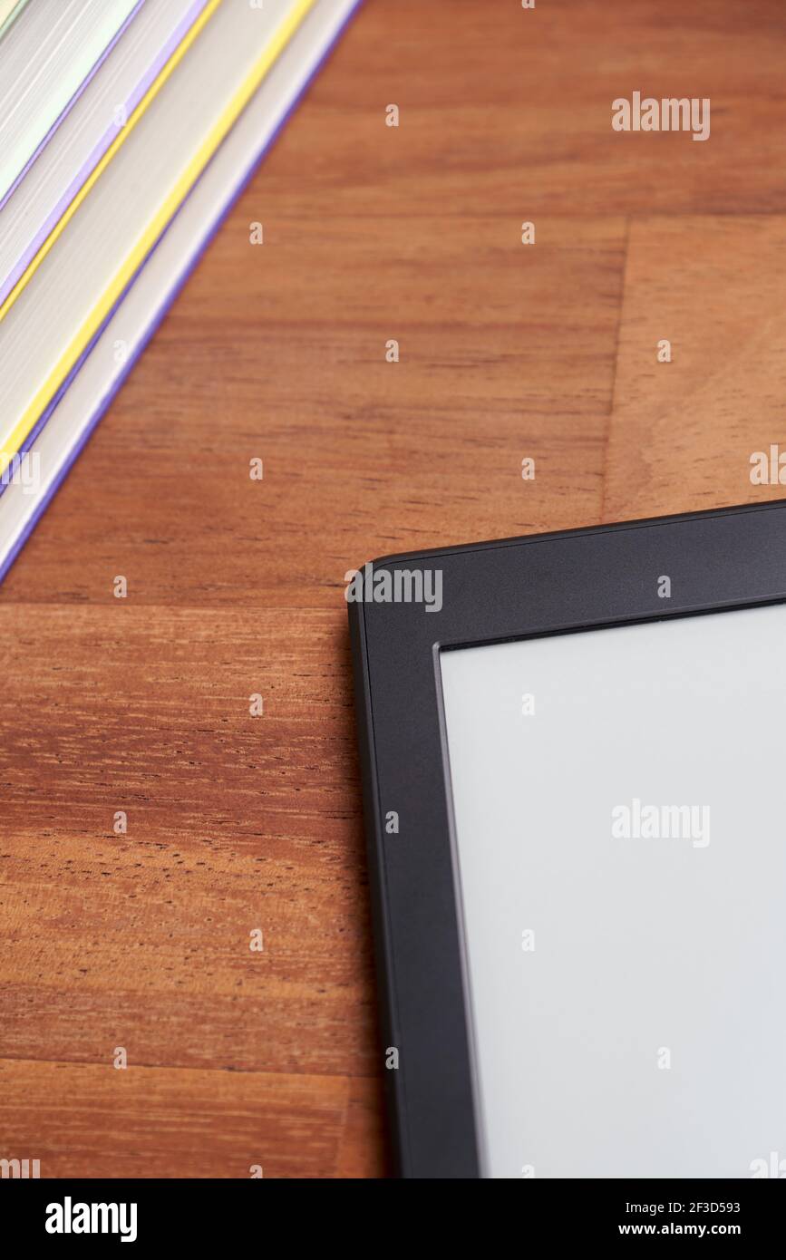 Student desk, pile of books and electronic reader with blank screen on