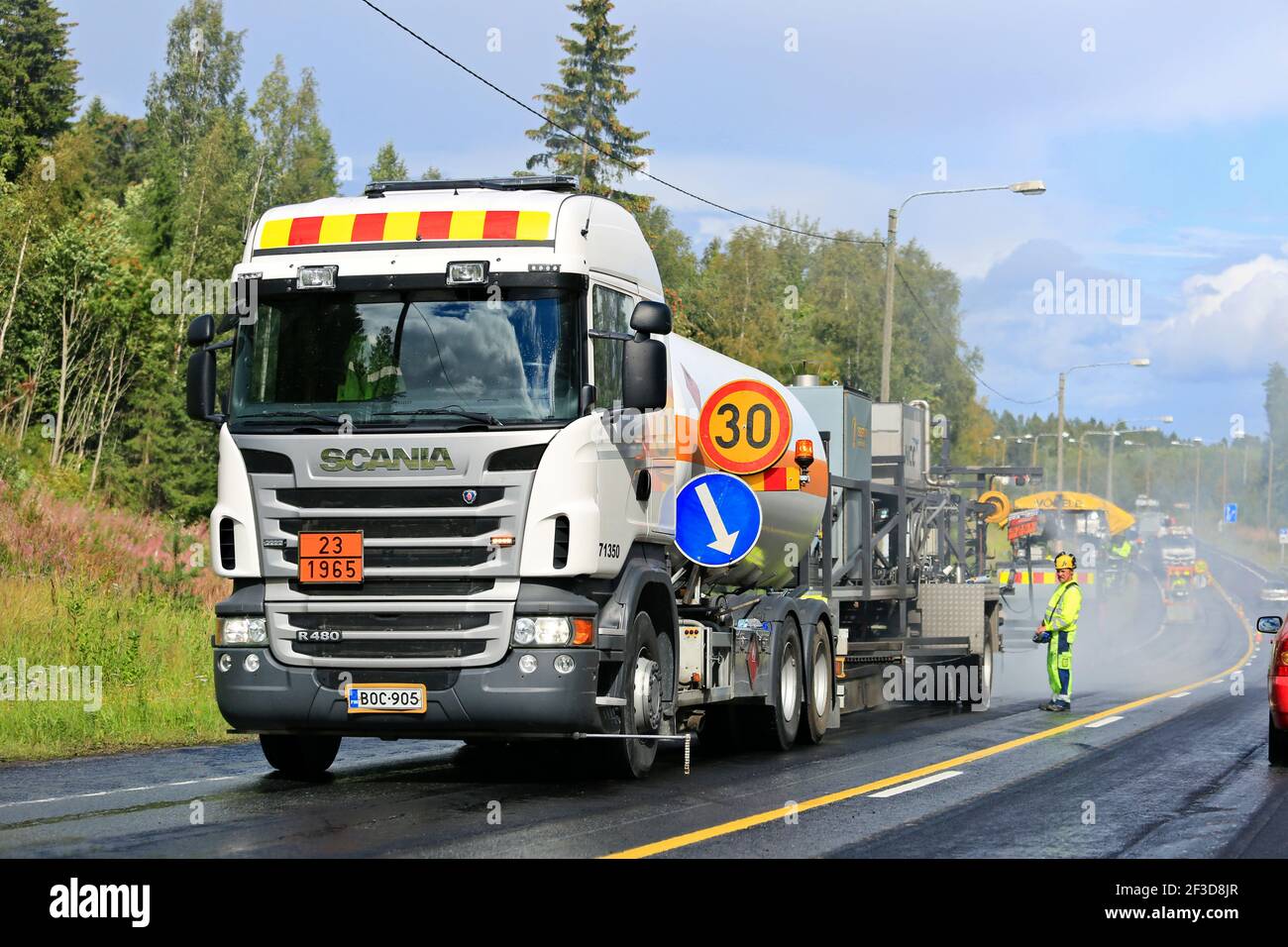 Scania bitumen truck with men and asphalting roadworks equipment at work, highway closed to one direction. Finland. Stock Photo
