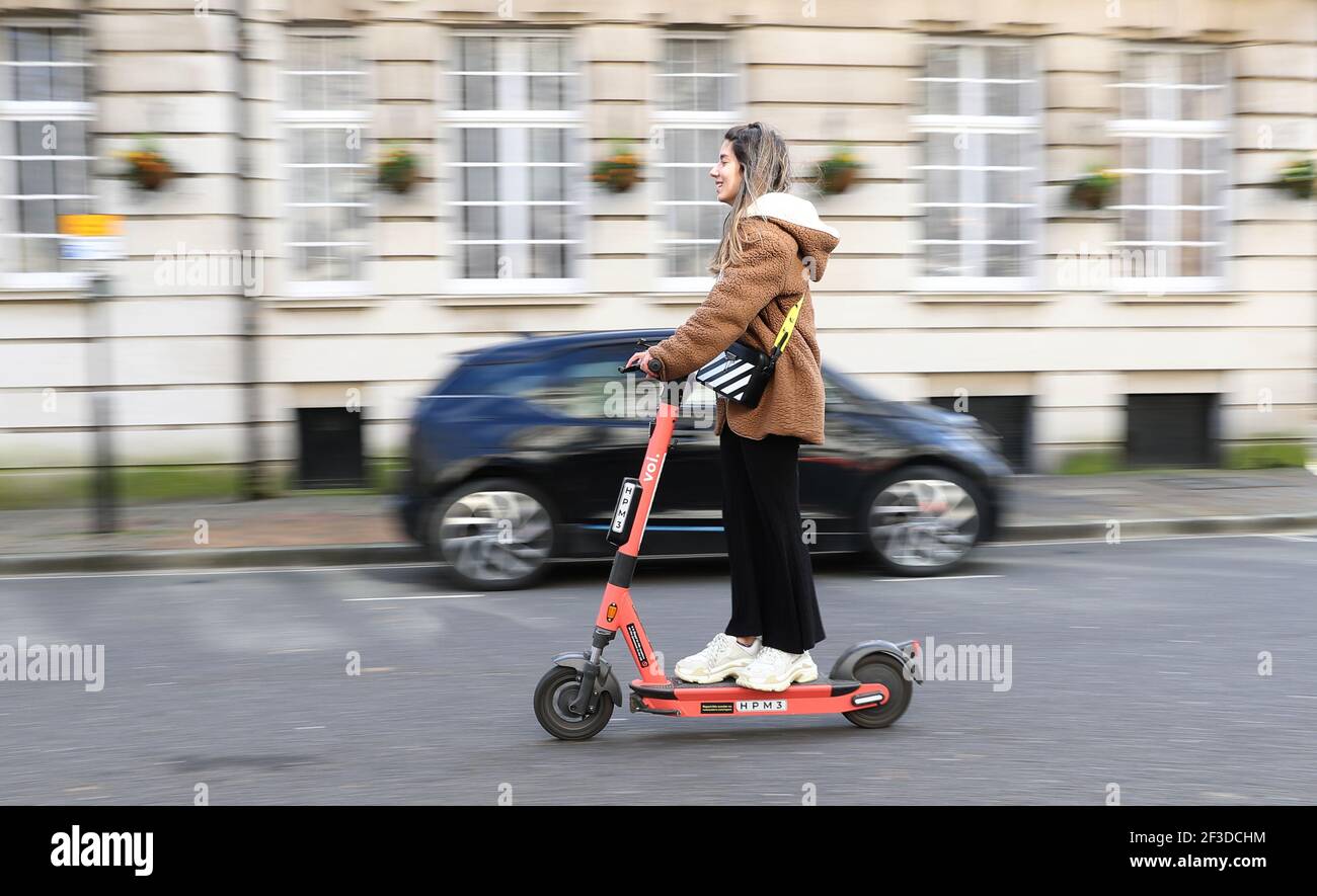 A person rides a Voi rental escooter near to the Guildhall in
