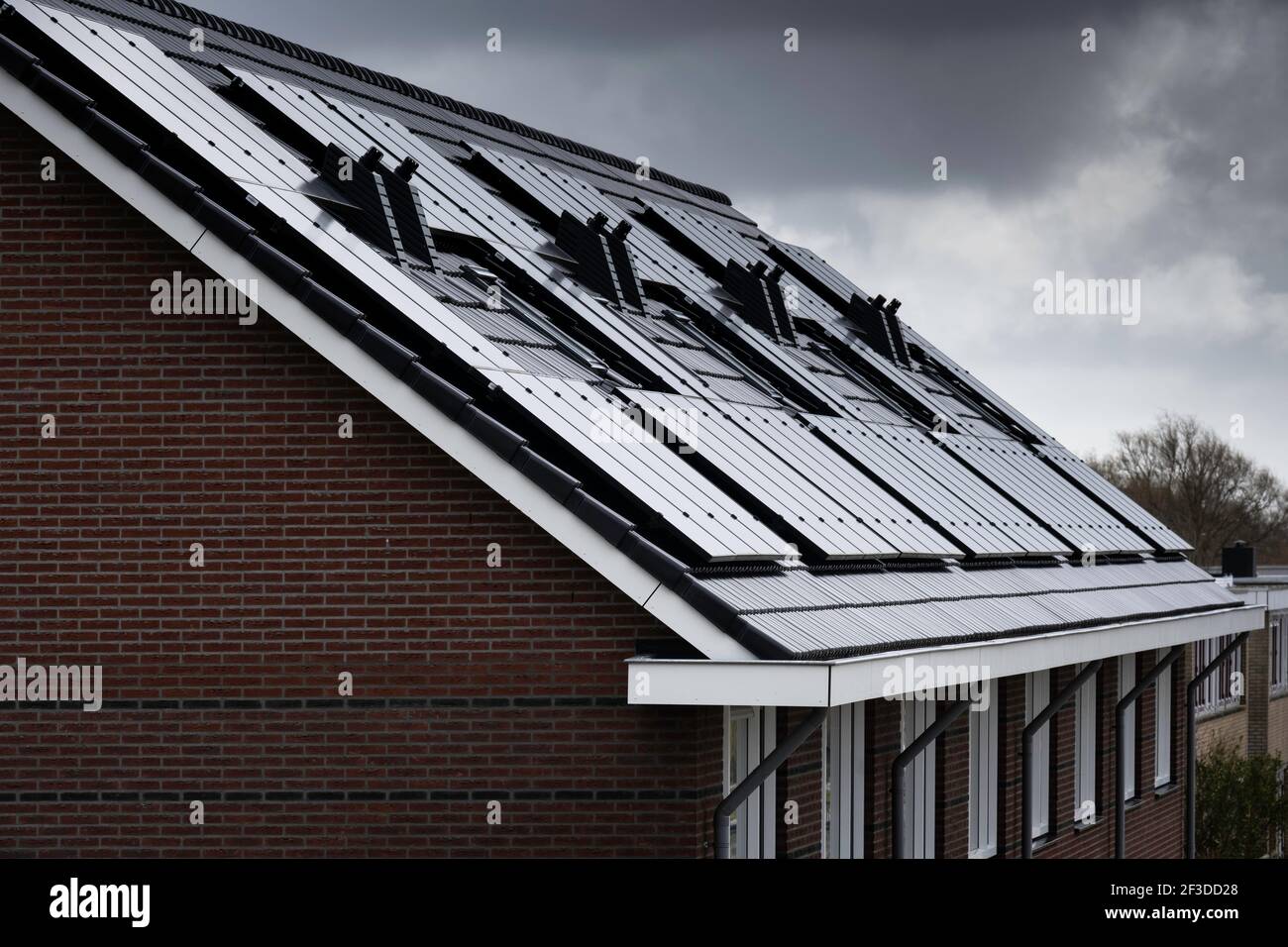 Solar panels mounted on the roof of modern new-build homes in Lemmer, Friesland, The Netherlands on a heavily overcast day. Is there enough sunlight? Stock Photo