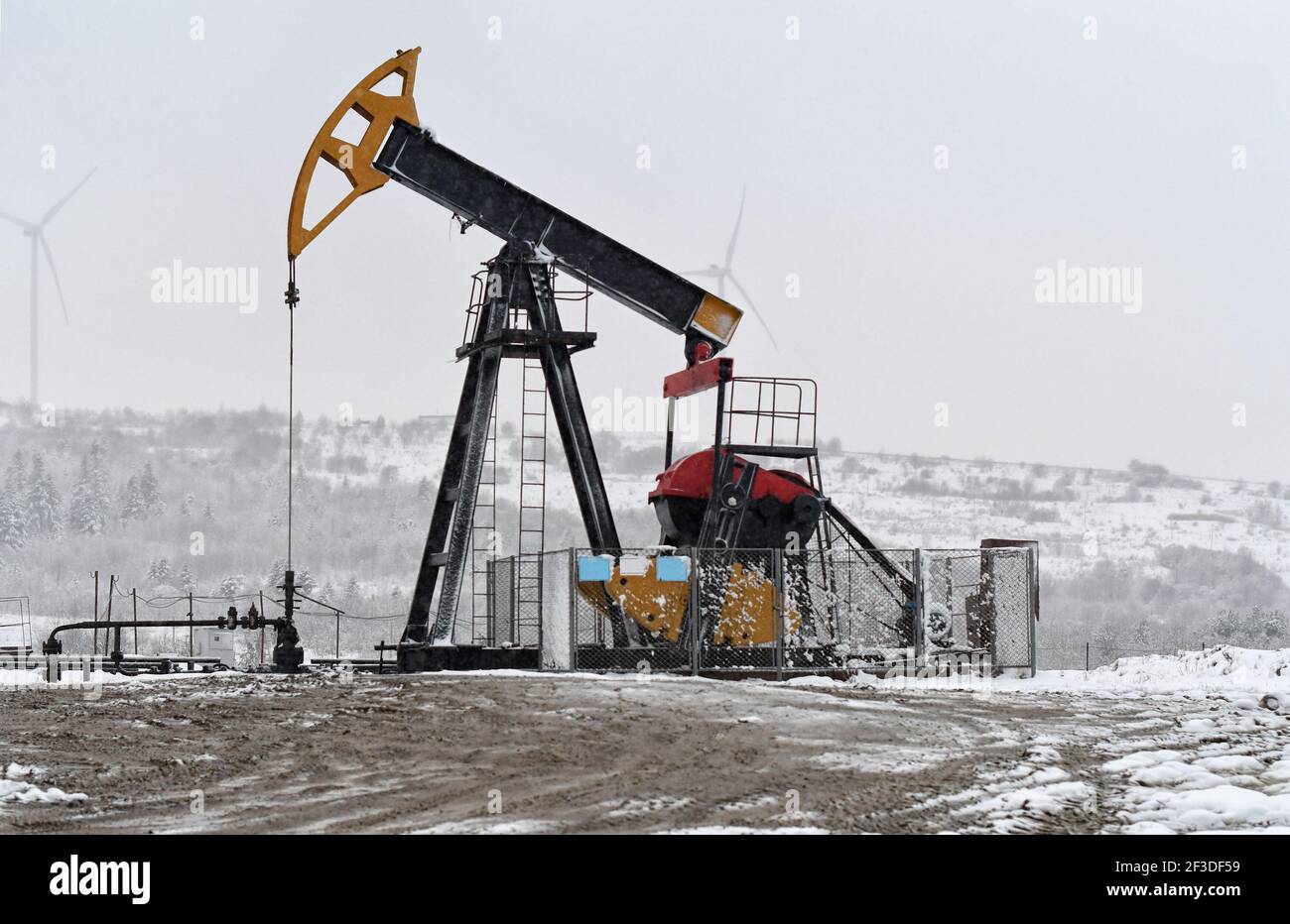 Oil pump. Oil and gas industry equipment. Oil field pump jack and oil refinery in the winter
