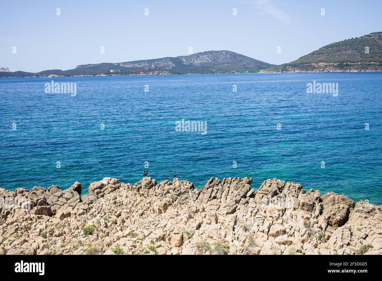 Landscape of Stones and rocks by river with mountains and blue sky in the background Stock Photo