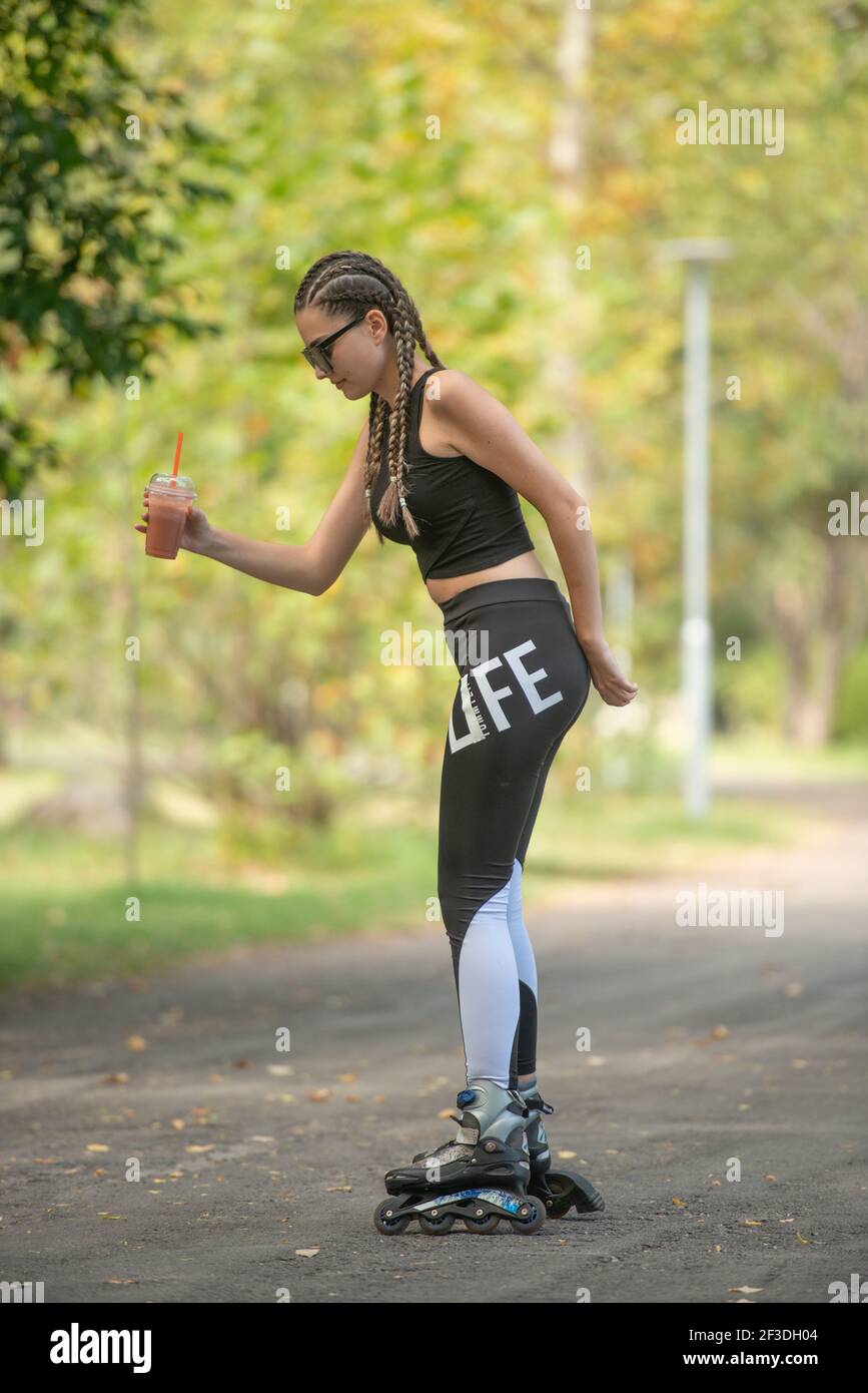 Young girl with hair braids learning to ride on roller skates and how
