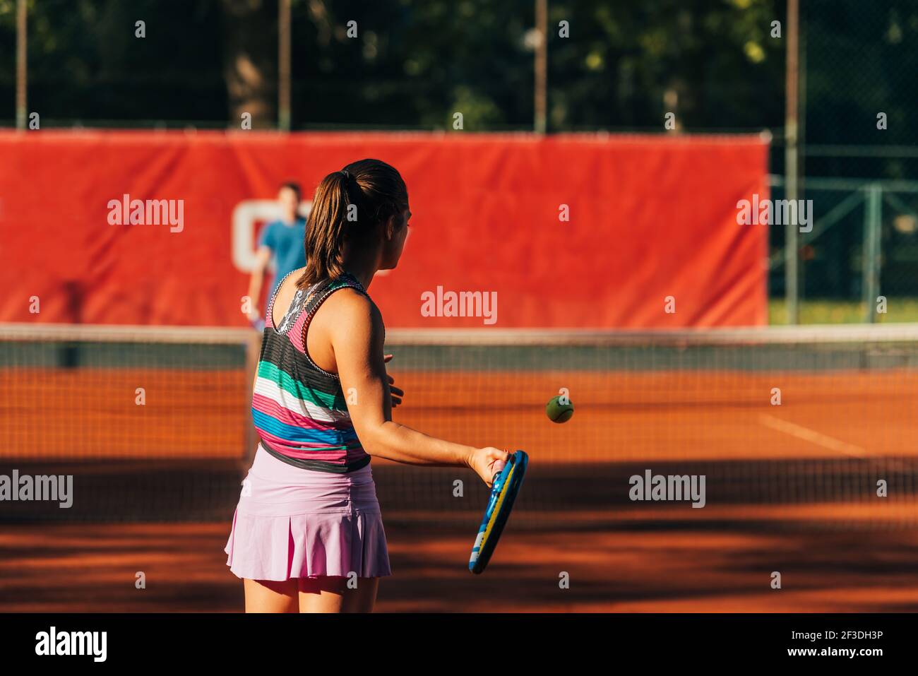 View from the back of a young female paying tennis on a court outside