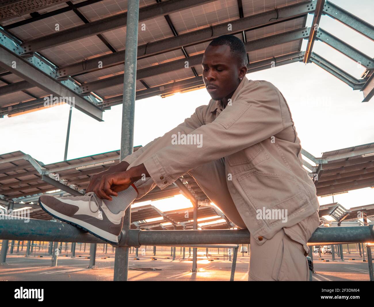 A handsome black Spanish male tying shoelaces in a parking lot Stock Photo Alamy