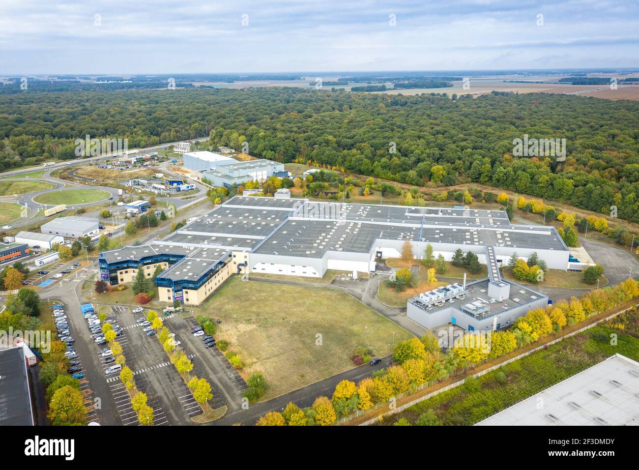 Drone view on production hall in industrial zone. Modern warehouse or production buildings surrounded by trees. Industry, transport and logistics. Stock Photo