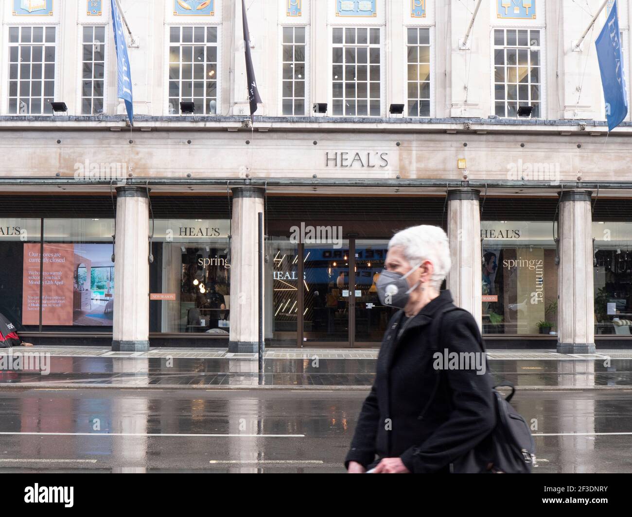 person wearing ppe mask walks past Heal's furniture store during