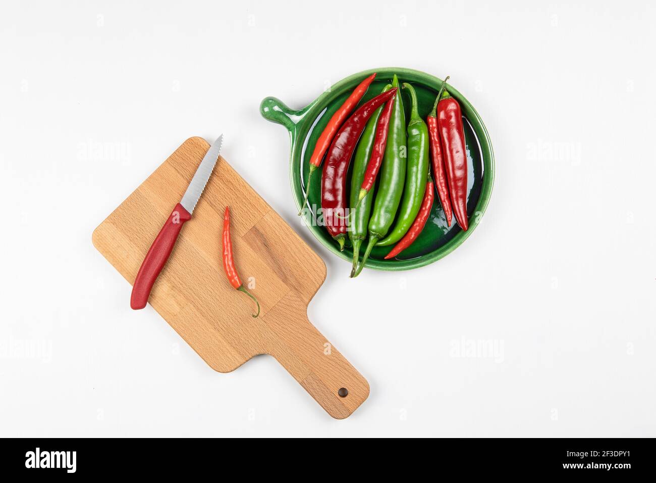 Green and red hot chilli peppers on green plate, red pepper on a wooden ...