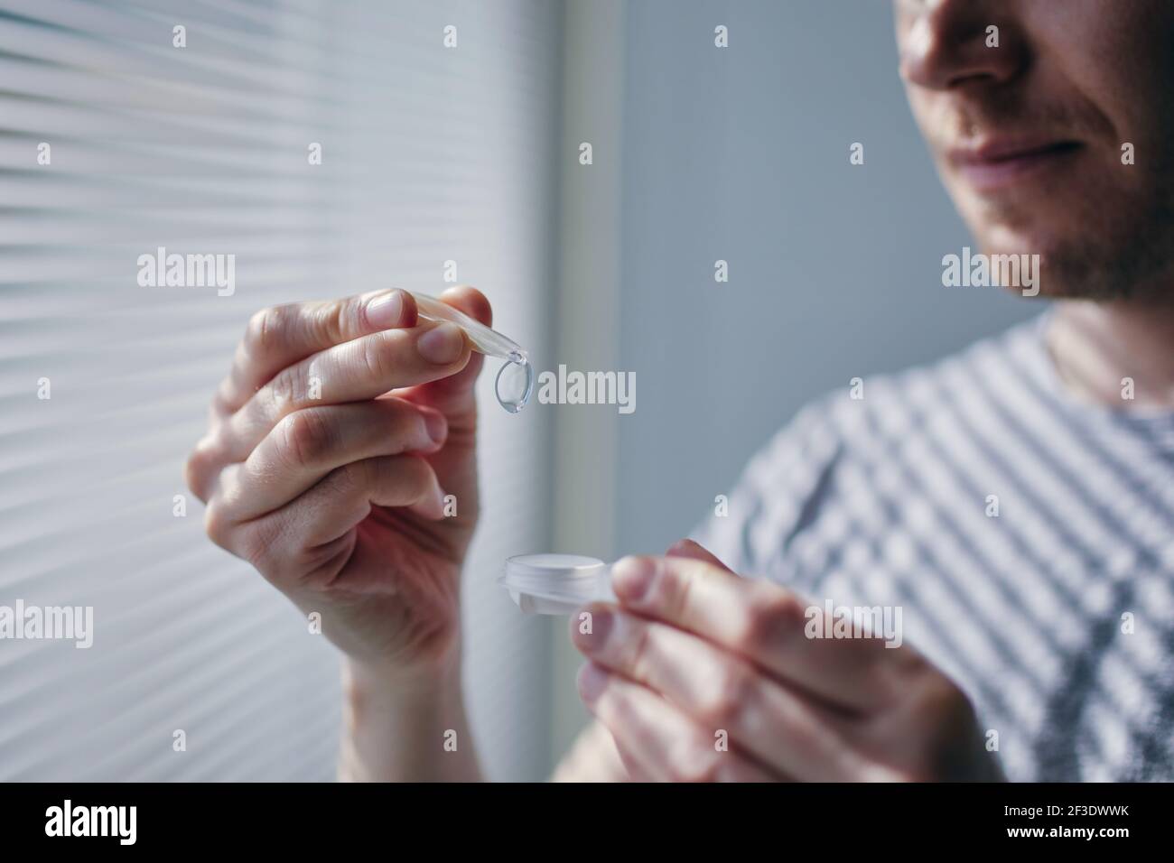 Young man opening contact lens case. Themes eyesight and daily routine. Stock Photo