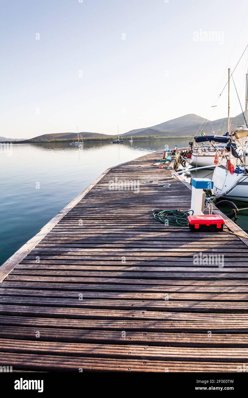 wooden gangway in marina with boats moored. Location is in Porte Conte nature reserve in Sardinia Stock Photo