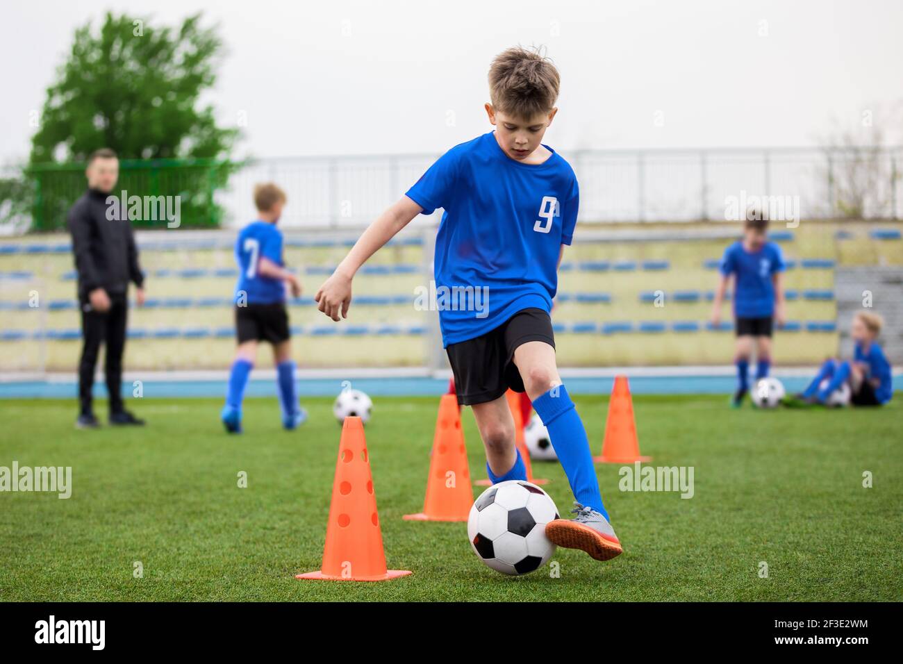 Boys attending soccer training on school field. Young man coaching