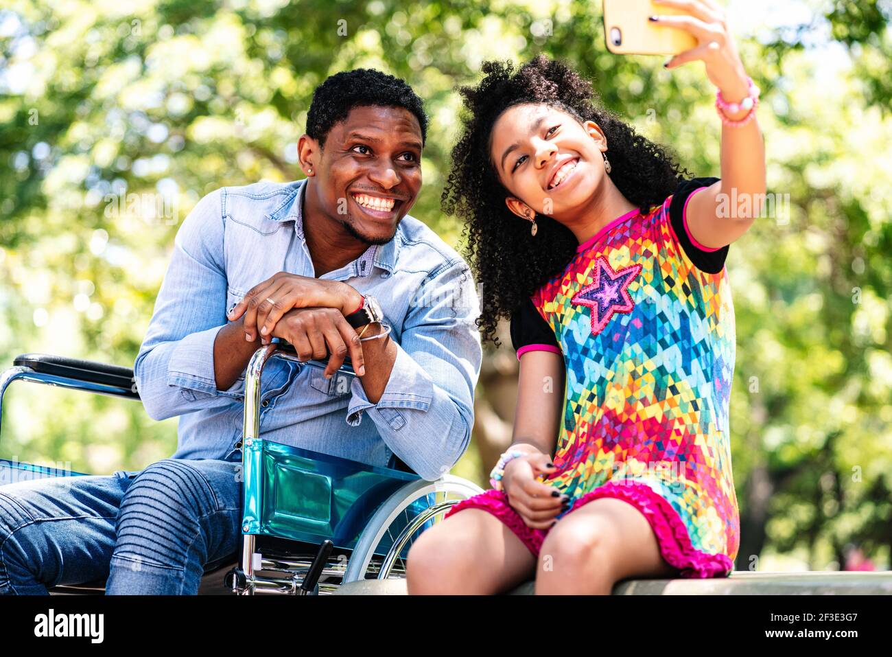 Man in a wheelchair taking a selfie with her daughter Stock Photo - Alamy
