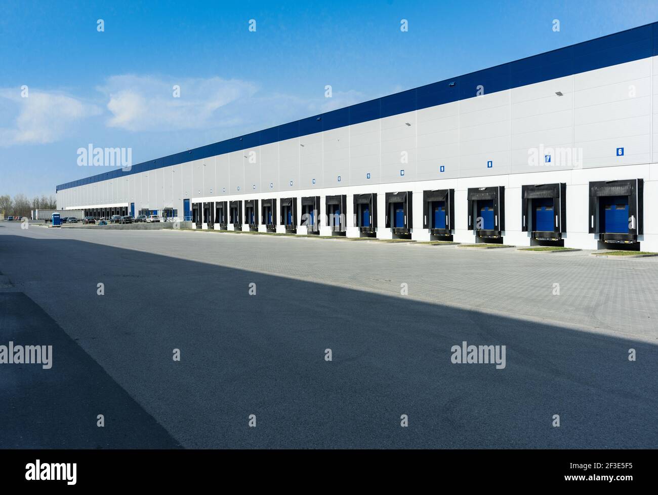 Wide view of loading bays on wall of large logistic hall. Long row of docks illuminated by sun. Transport and logistics concept. Stock Photo
