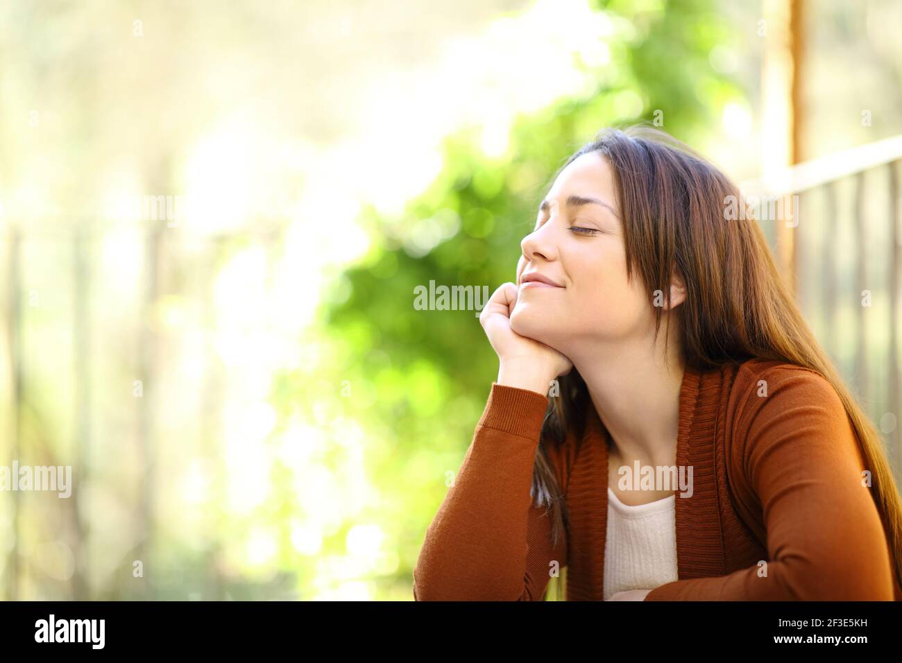Satisfied woman relaxing with closed eyes breathing fresh air in a garden at home Stock Photo
