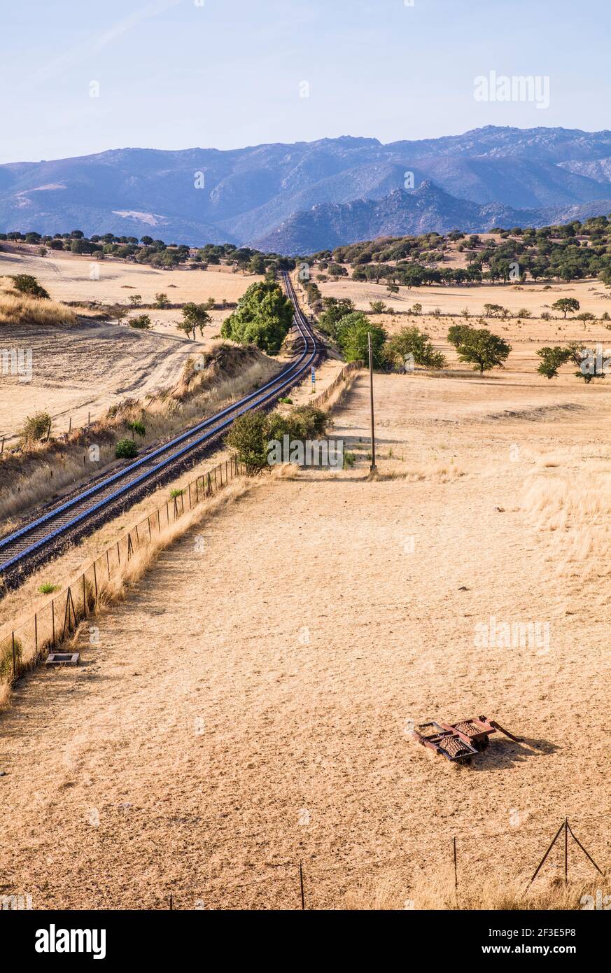 Railway line in Sardinia.  Railway lines running through dry countryside fields with mountains in the distance and blue skies Stock Photo