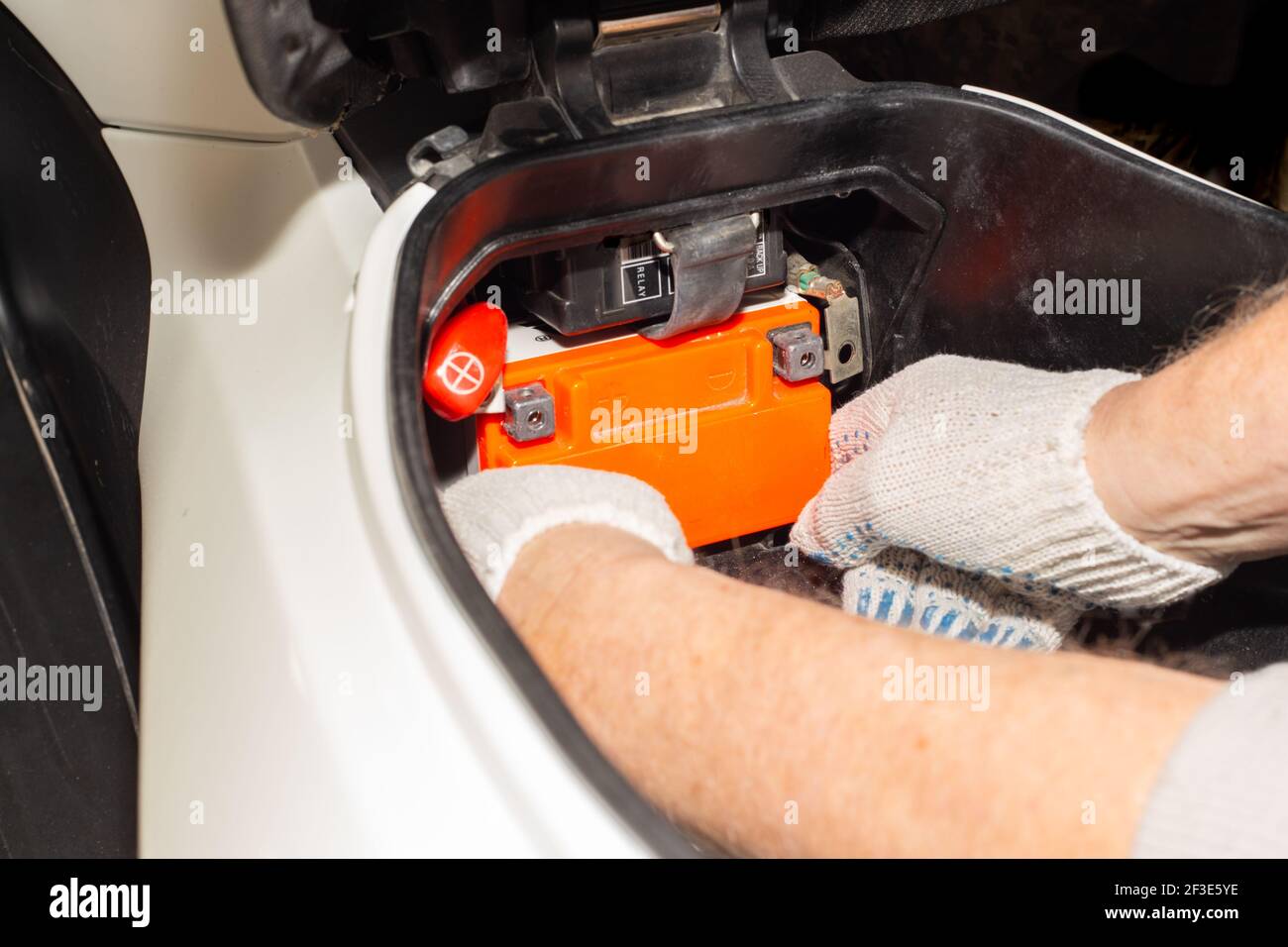 Replacing the motorcycle battery. An auto mechanic in a car service