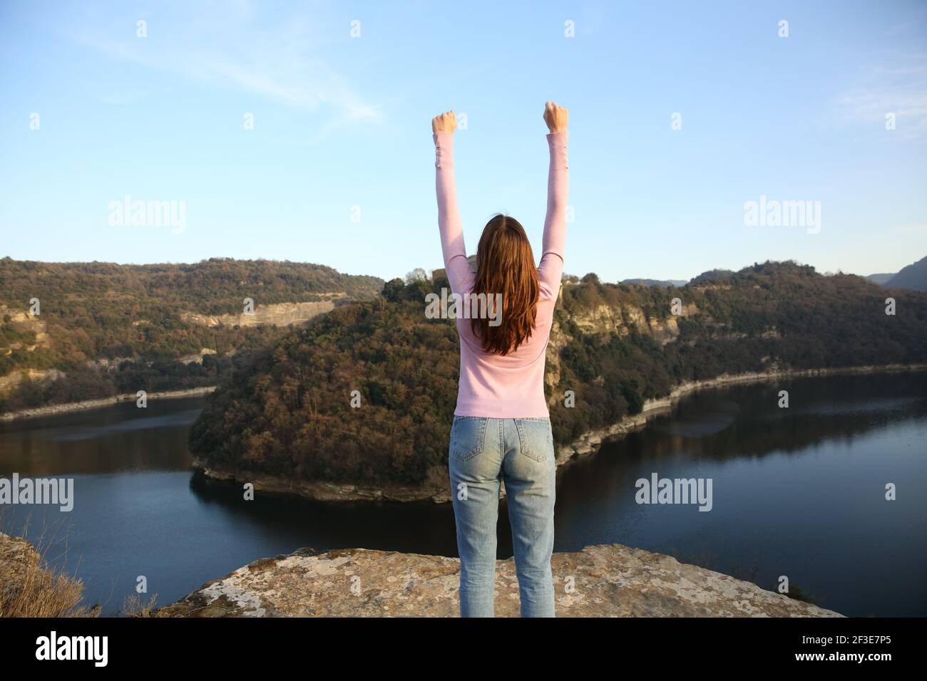 Back view portrait of a woman raising arms celebrating vacation in a river Stock Photo