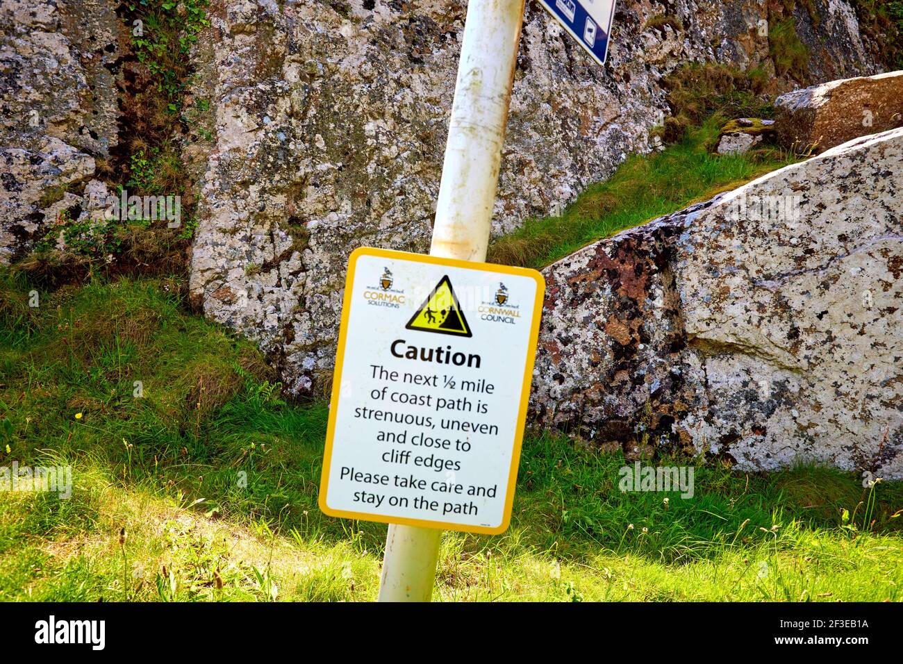 Sign warning that the coast path is strenuous and uneven near to Lamorna Cove in Cornwall Stock Photo