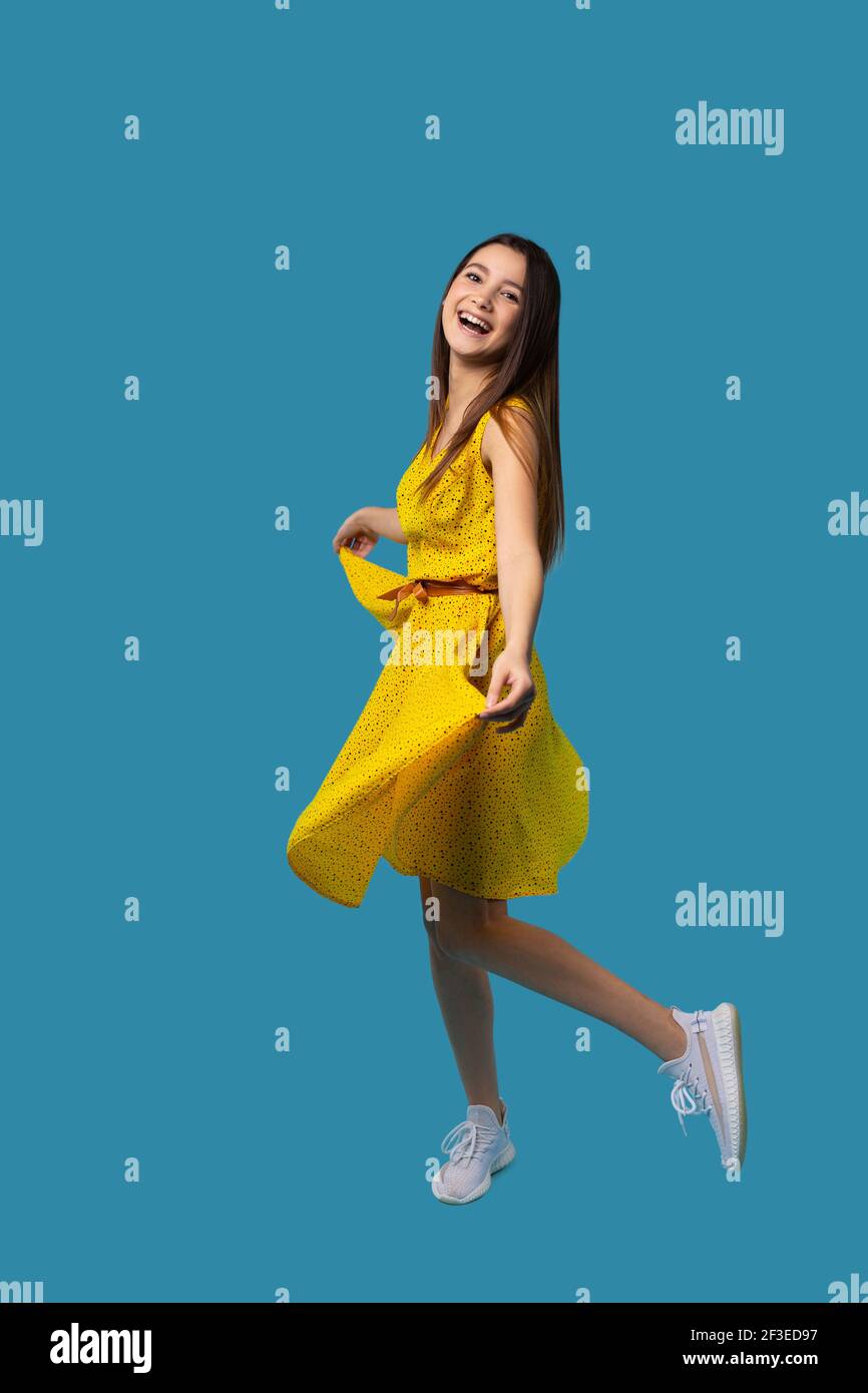 Happy caucasian girl in a bright yellow dress smiles and poses on a ...