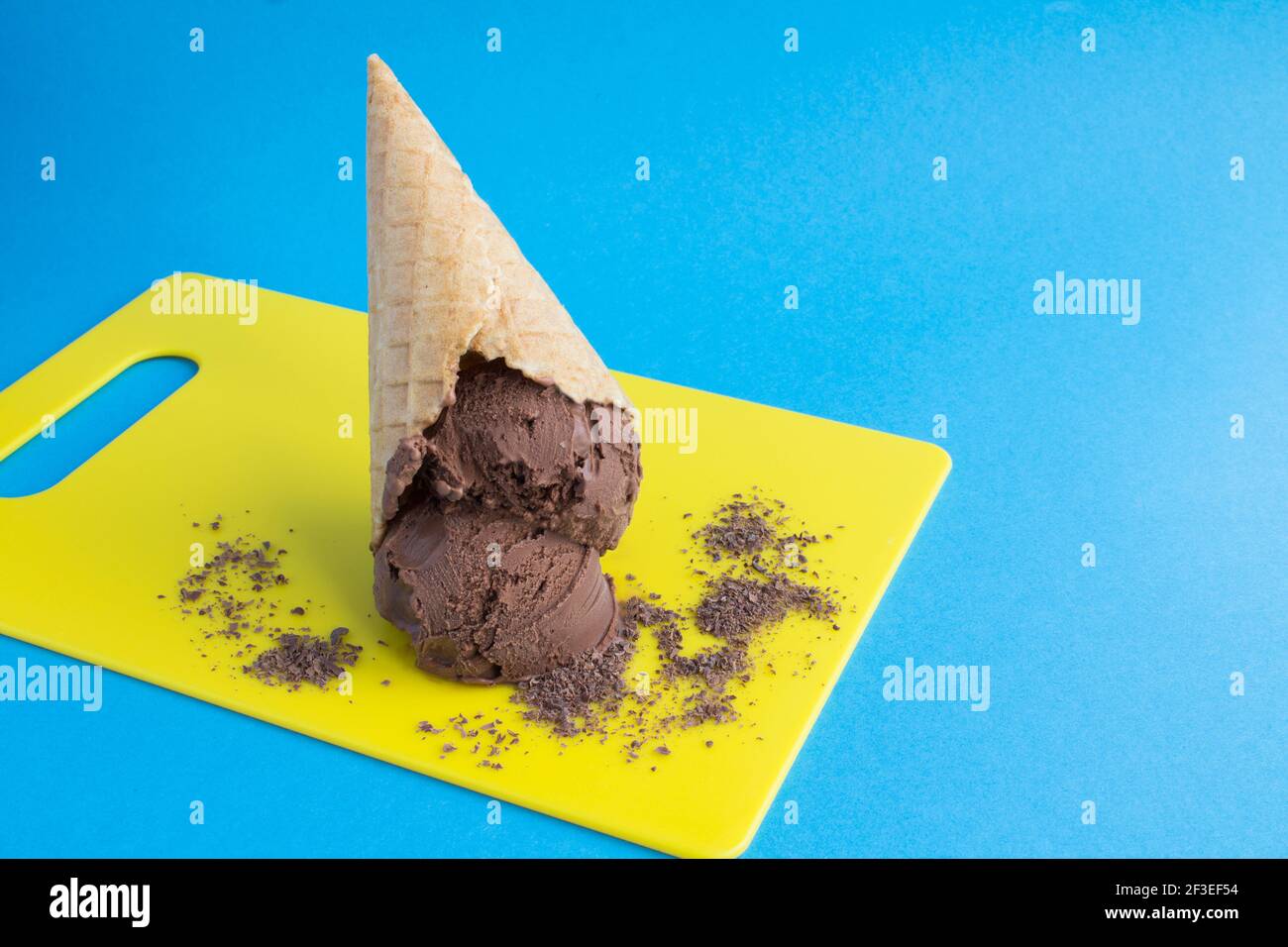 Chocolate ice cream in a waffle cone on the yellow cutting board on the ...
