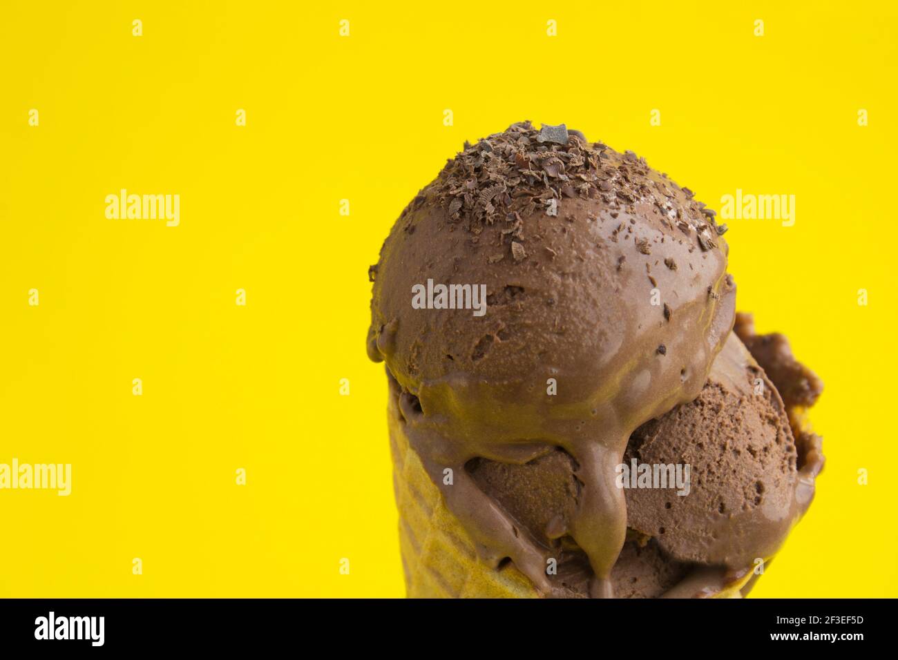 Close-up on chocolate ice cream in a waffle cone on the yellow ...