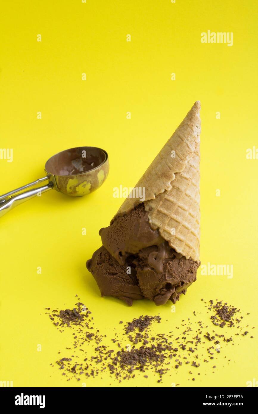 Chocolate ice cream in a waffle cone on the yellow background. Location ...