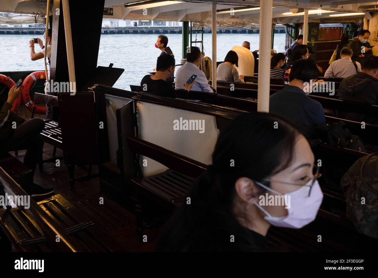 Hong Kong, China. 16th Mar, 2021. Commuters wearing face masks as a precaution against the spread of coronavirus cross the Victoria Harbour on a ferry. A series of new coronavirus (COVID-19) cases emerged at major banks and law firms in Central district, the business centre of the city, as Hong Kong reported a spike of new infections. Credit: SOPA Images Limited/Alamy Live News Stock Photo