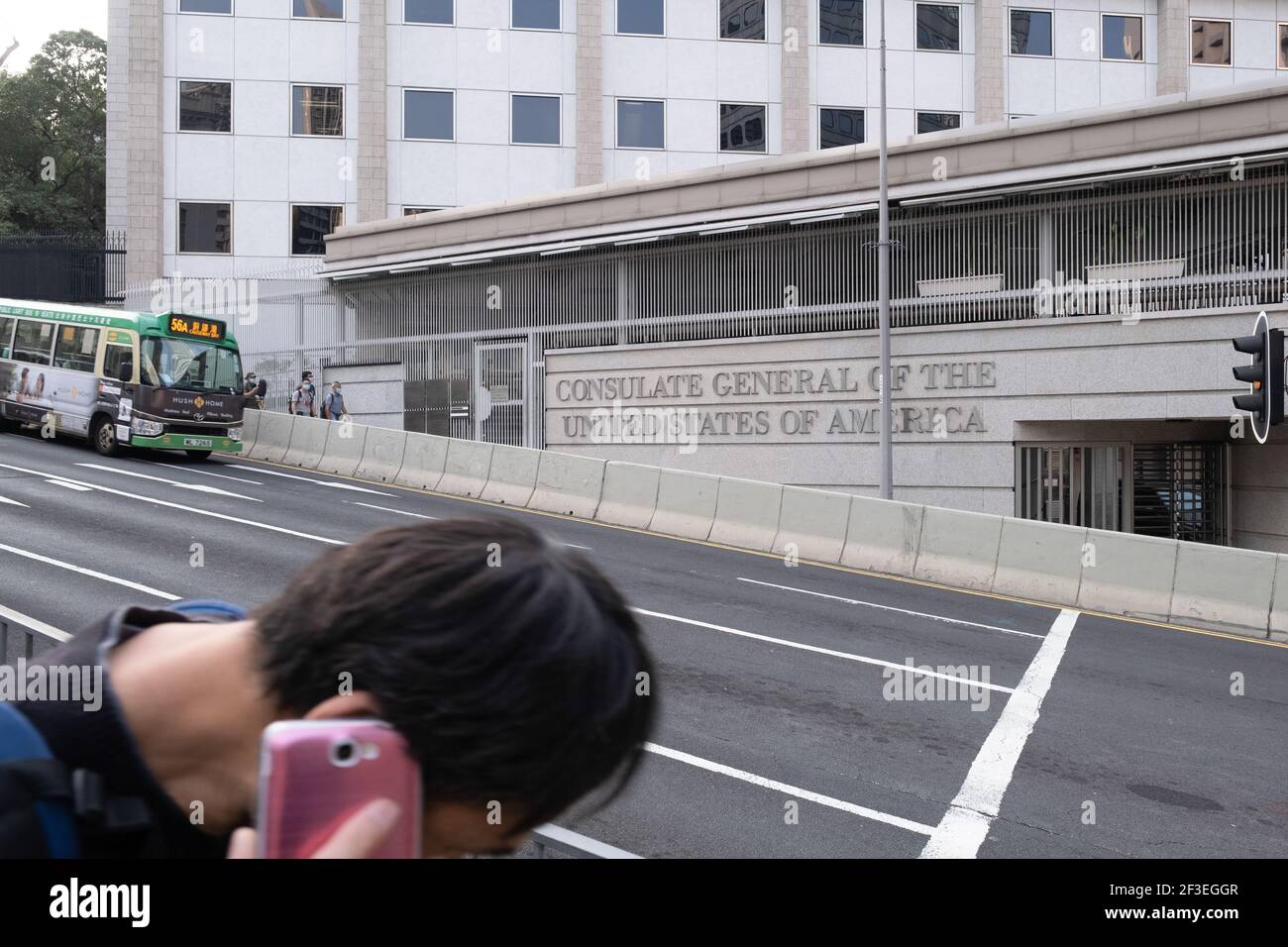Hong Kong, China. 16th Mar, 2021. A man talking on a mobile phone walks past the Consulate General of the United States of America in Hong Kong. The U.S. Consulate General has been closed following the announcement that two employees have tested positive for COVID-19. A series of new coronavirus (COVID-19) cases emerged at major banks and law firms in Central district, the business centre of the city, as Hong Kong reported a spike of new infections. Credit: SOPA Images Limited/Alamy Live News Stock Photo