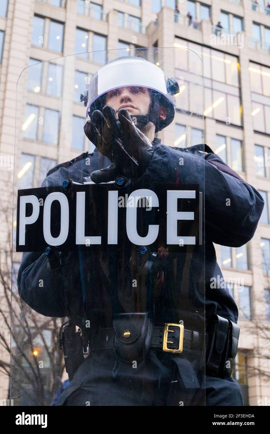 A police riot officer with shield and helmet, confronts protestors. At ...