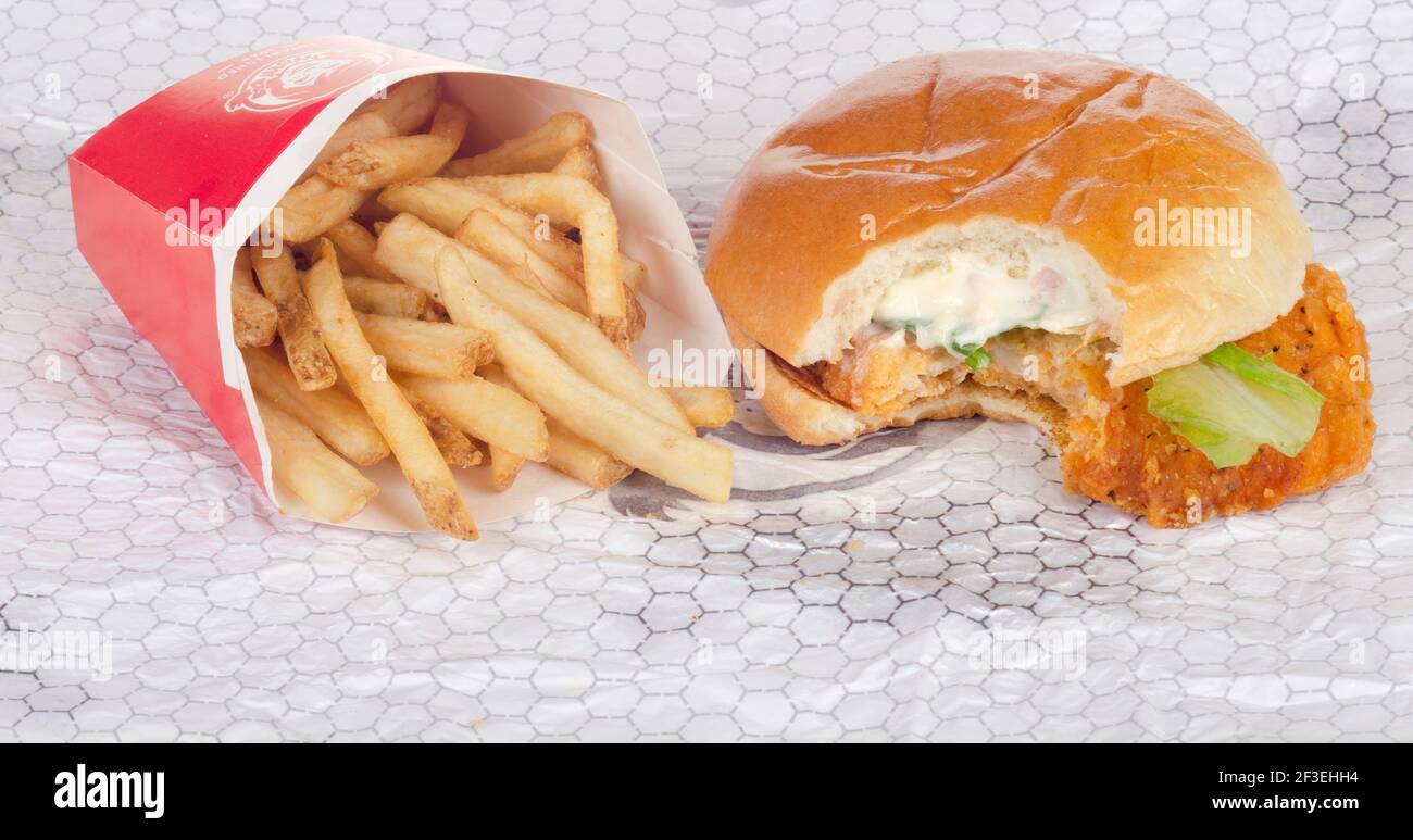 Wendy's Spicy Chicken Sandwich with Bite Taken on Wrapper with French Fries aka Chips Stock Photo