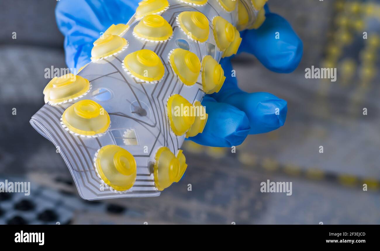 Silicone flex printed circuit board curled to a roll on computer keyboard membranes background. Engineer hand with plastic flexible PCB. Yellow button. Stock Photo