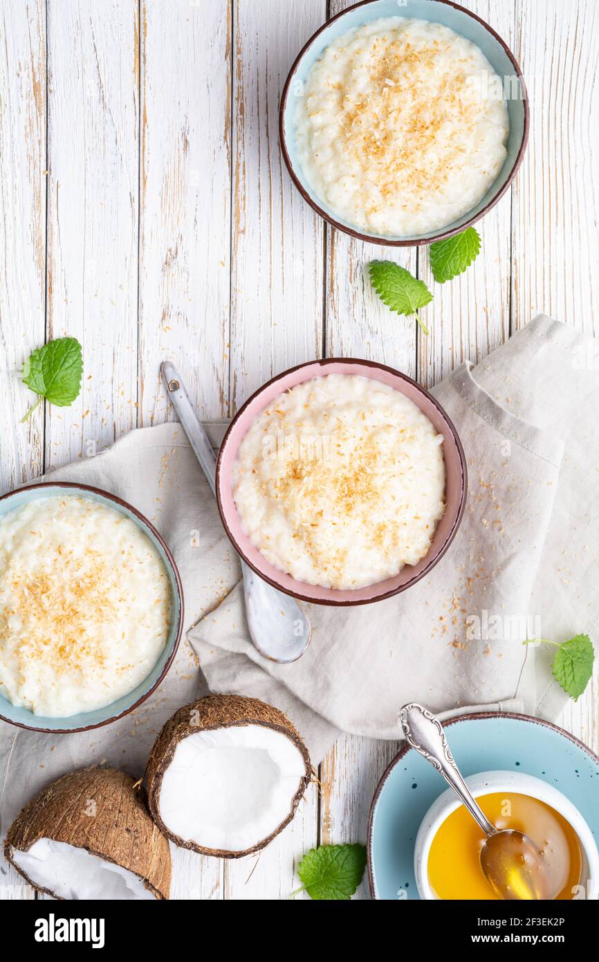 Sweet and creamy coconut rice pudding with honey, topped with grated and toasted coconut in a ceramic bowl Stock Photo