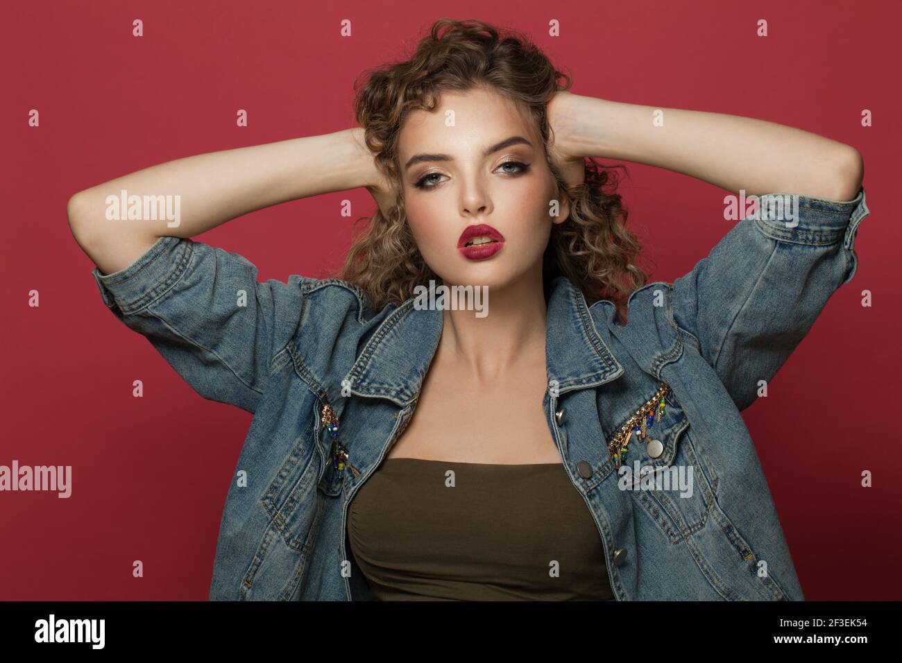 Pretty young woman with curly hair on red background Stock Photo - Alamy