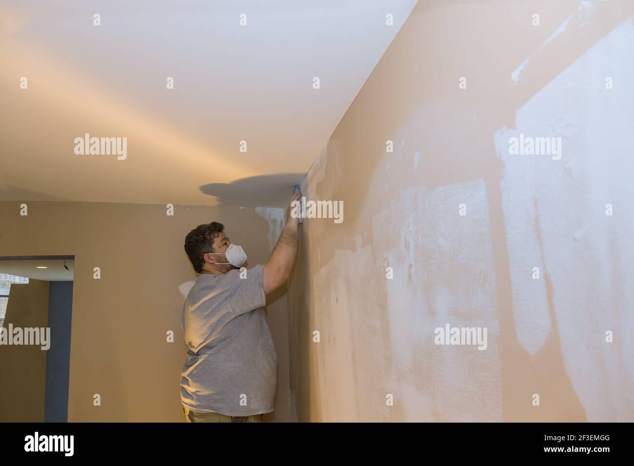 Man sanding the plaster plasterboard in drywall Stock Photo Alamy