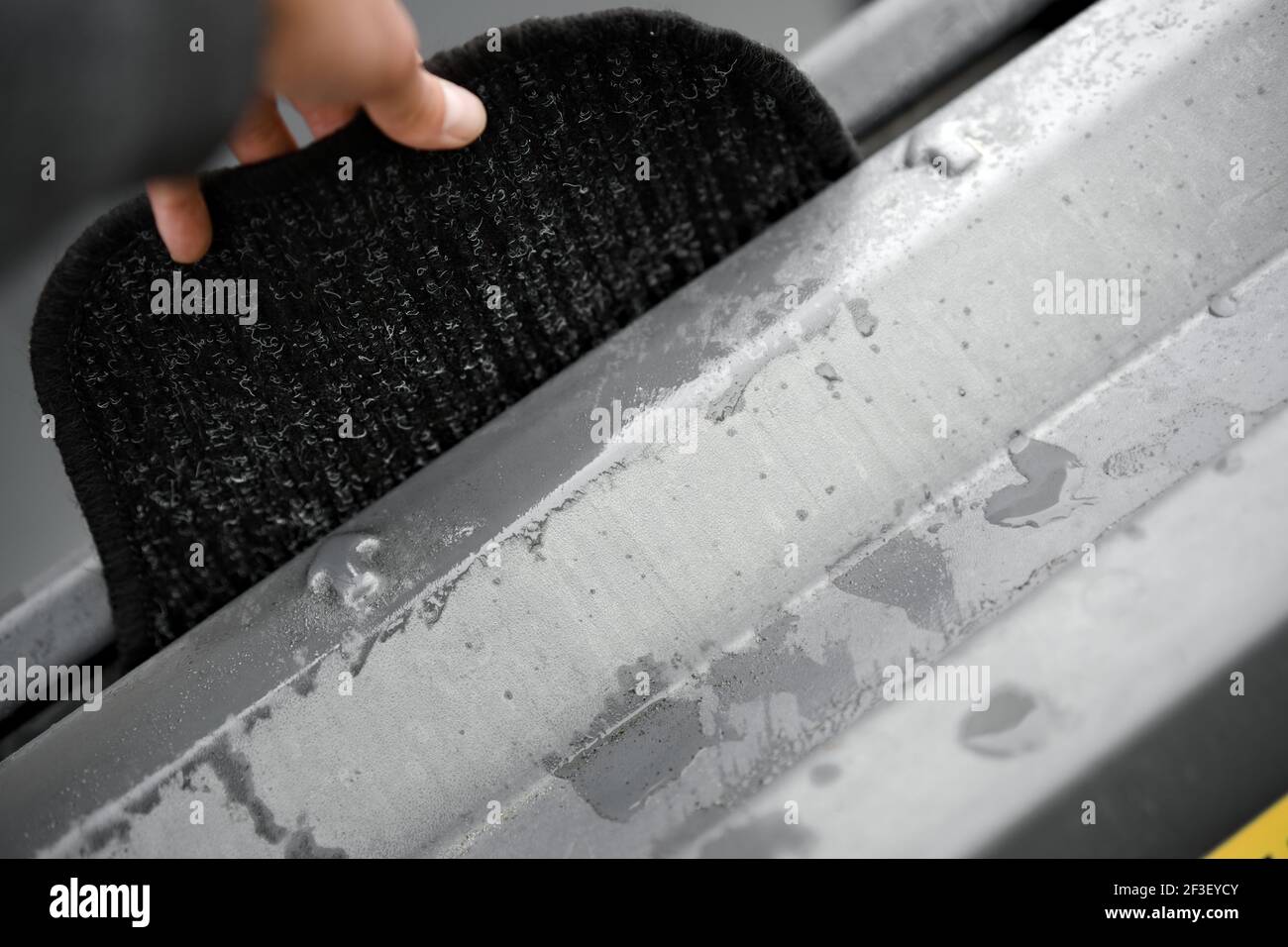 Person washing car floor mat mats at carwash cleaning machine Stock Photo