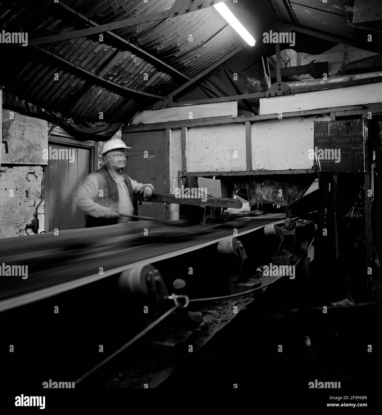 Labourer checking coal on conveyor belt on surface at Monkwearmouth Colliery Stock Photo