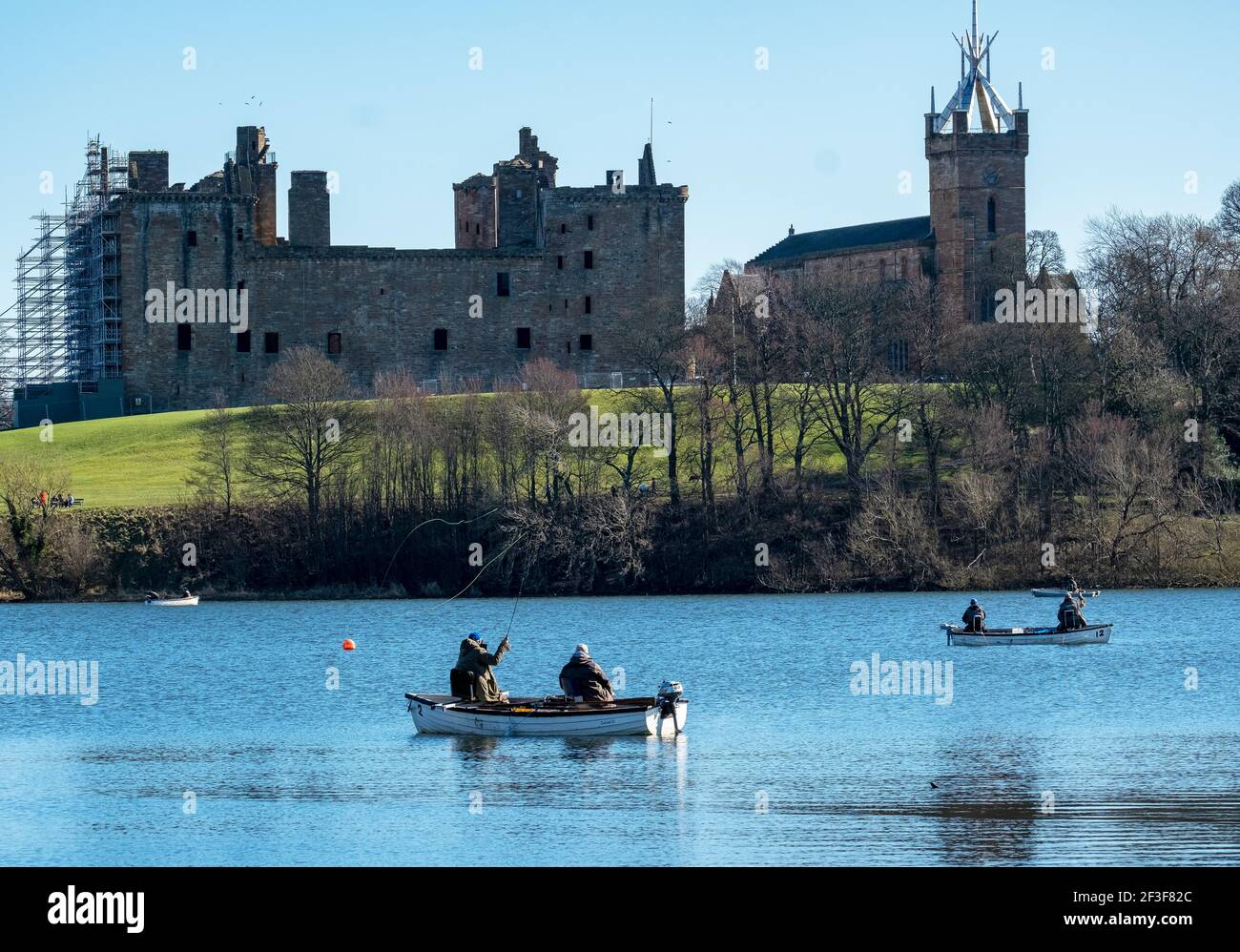 Men fly fishing from boats on Linlithgow Loch with Linlithgow Palace behind. Stock Photo