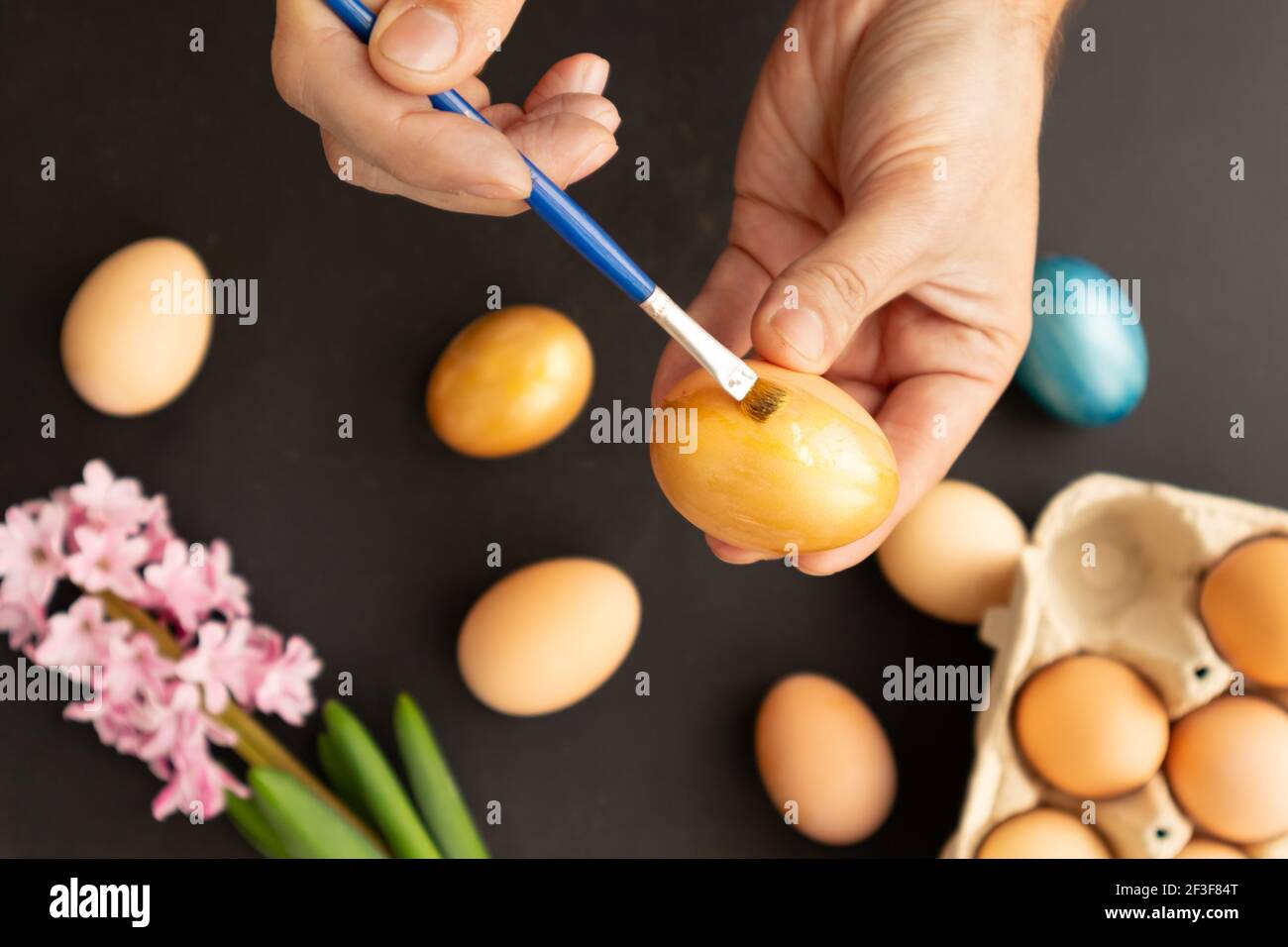Preparing for Easter. Father painting Easter eggs on black background. Easter day. Stock Photo