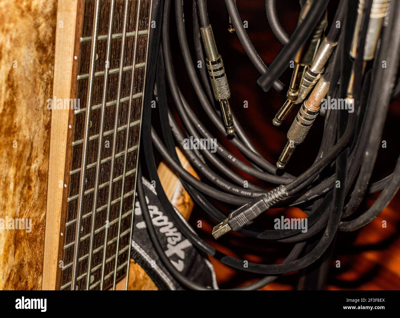 Shot of a wooden 5 strings electric bass guitar with jacks and cables