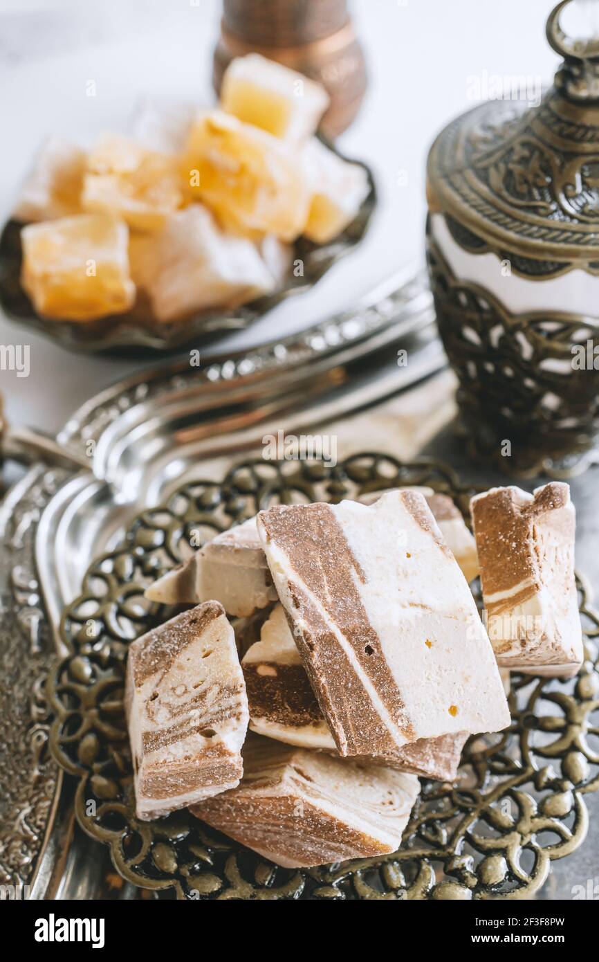 a vase with various pieces of halva and oriental sweets on a light background. Close-up of halva. Stock Photo
