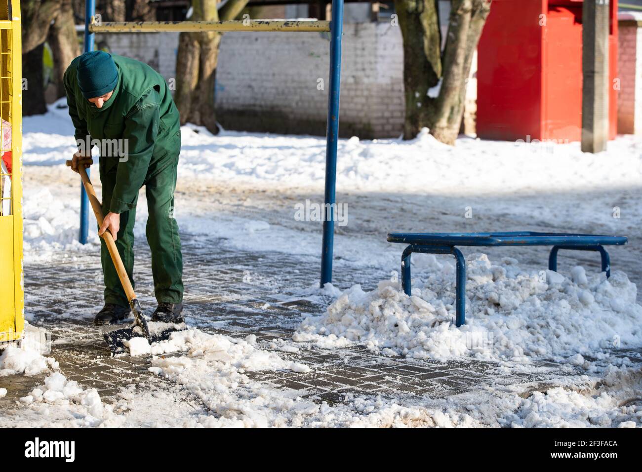A worker uses a metal spade to break frozen pieces of ice off the