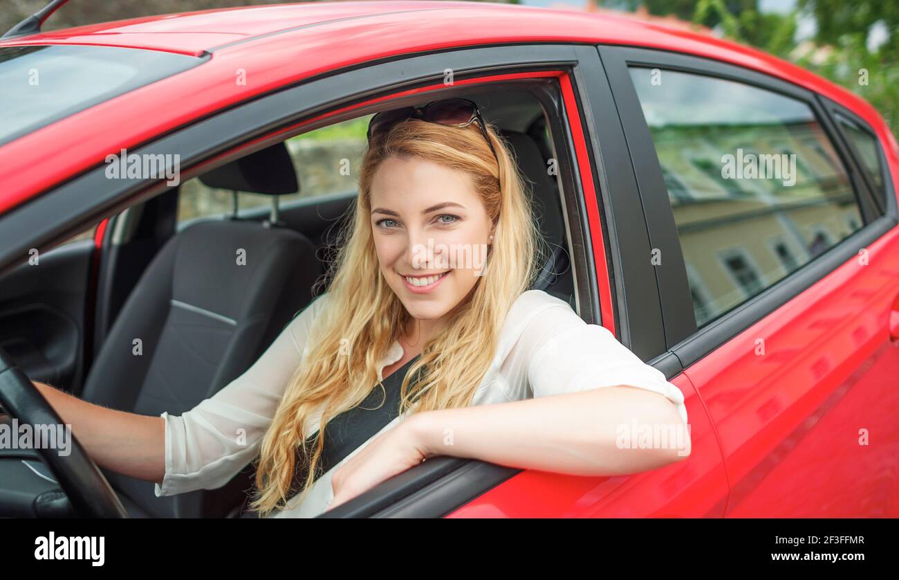Happy beautiful woman is driving a red car Stock Photo - Alamy