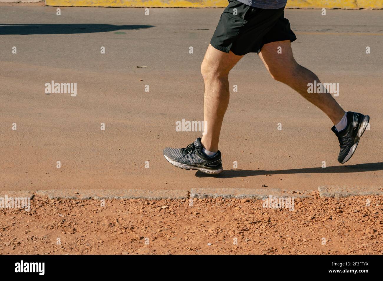 Runner feet running on road closeup on shoe. Peoples fitness sunrise jog workout welness concept. Stock Photo